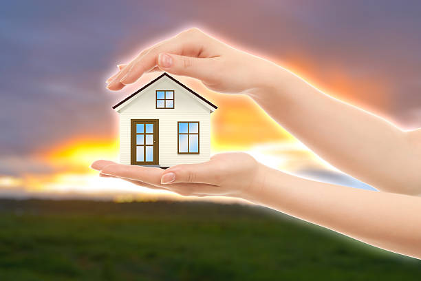 Picture of woman's hands holding a house against nature stock photo