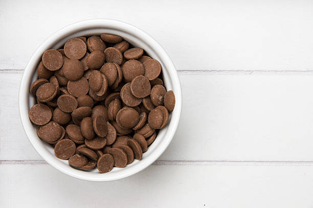 white bowl with chocolate pieces white bowl filled with chocolate pieces on a wooden surface chocolate chip cookie top view stock pictures, royalty-free photos & images