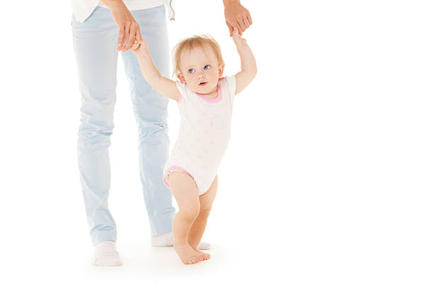 baby boy doing first steps with mother's support. baby boy doing first steps. mom and toddler son playing in living room. motherhood, family, love, parenthood, early development