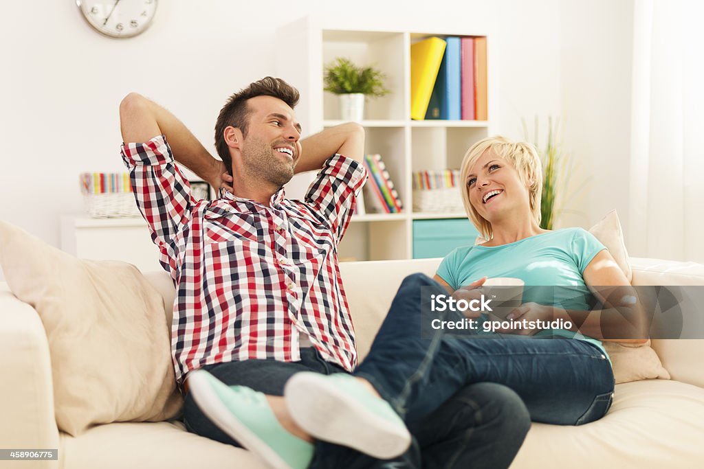 Feliz casal relaxando na sala de estar - Foto de stock de Aconchegante royalty-free