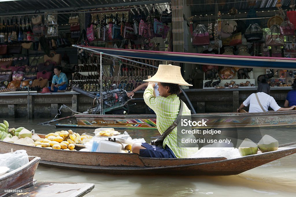 vendor at Damnoen Saduak floating market, Thailand "Damnoen Saduak, Thailand - July 4, 2012: market vendor paddling in a boat full with bananas and guava at the Damnoen Saduak floating market. The Damnoen Saduak floating market is a well-known travel destination for tourists visiting Thailand." Adult Stock Photo