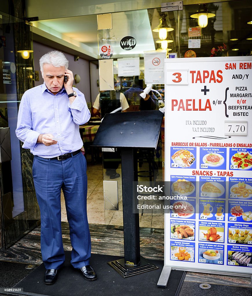 Homem falando no celular perto da entrada do café - Foto de stock de Adulto royalty-free