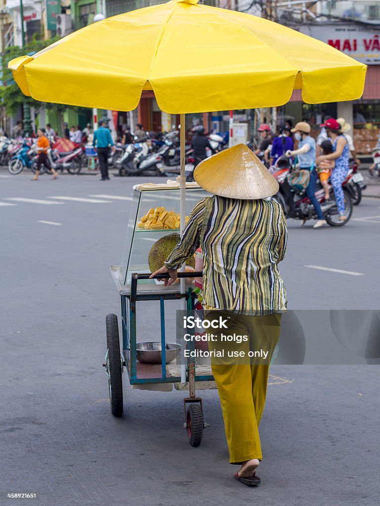 Ho Chi Minh City, Vietnam "Ho Chi Minh City, Vietnam - July 5, 2012: Street vendor wearing a conical hat pushes a mobile cart containing fresh jackfruit near the Ben Thanh Market in Saigon." 2012 Stock Photo