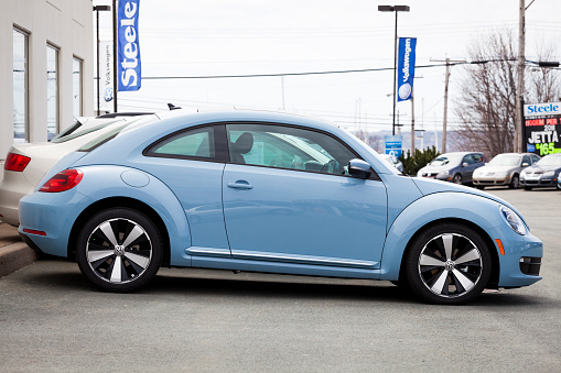 Dartmouth, Nova Scotia, Canada - April 15, 2012: A 2012 Volkswagen New Beetle is parked on a car dealership lot.  Side profile of vehicle.  Other cars for sale and advertisements can be seen in background.  The 2012 Volkswagen New Beetle was introduced in 2011 for a 2012 model year.  It is lower and wider than the New Beetle is replaces.