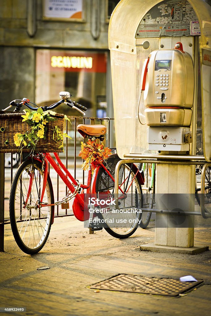 Bicicleta con flores estacionada cerca de públicos teléfono en Milán - Foto de stock de Otoño libre de derechos