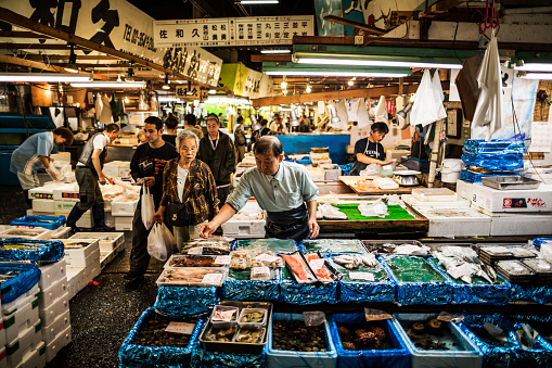 Tokyo, Japan - October 6, 2012: Buyers and sellers at the Tsukiji fish market in Tokyo. With an annually estimated turnover of 5.5 billion dollars and more than 60.000 workers ,this is the biggest wholesale and seafood market in the world.  With more than 2000 tons of seafood handled daily it is said that any eatable seafood can be found here. Because the installations are getting old and the space is getting too small for this numbers there are plans to move the market to another placement in 2014.