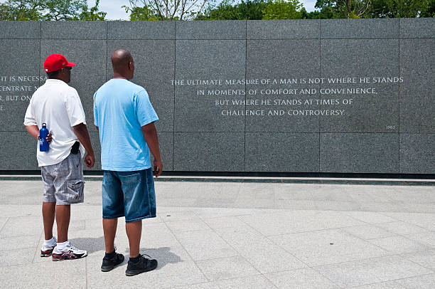 Visiting the Martin Luther King Jr Memorial in Washington DC Washington DC, USA - June 13, 2012: An African-American father and son stand together at the Martin Luther King Jr Memorial, inaugurated in 2011. They are looking at a quote by MLK which reads: THE ULTIMATE MEASURE OF A MAN IN NOT WHERE HE STANDS IN MOMENTS OF COMFORT AND CONVENIENCE BUT WHERE HE STANDS AT TIMES OF CHALLENGE AND CONTROVERSY. martin luther king jr images stock pictures, royalty-free photos & images