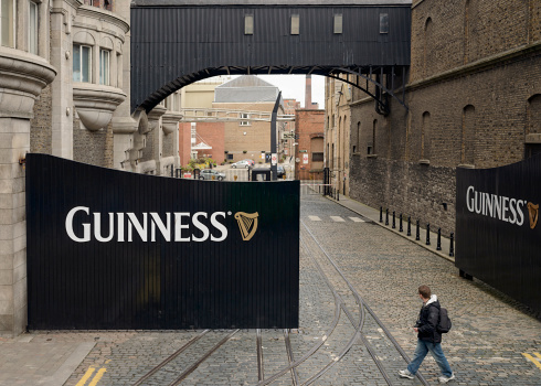 Dublin, Ireland - May 5, 2012: A man walking past large entrance gates to the St. James's Gate Brewery in Dublin, where Guinness has been made since 1759.
