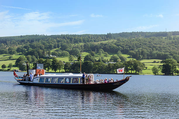 View across lake Windermere in Cumbria, UK.  Boats can be seen moored on the lake and people can be seen on the bats and on the promenade