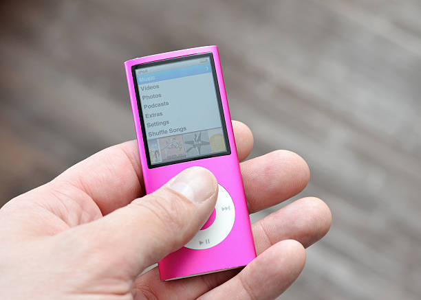 iPod Nano "Vancouver, Canada -- September 12, 2012:Close up of a man's hand holding an older version of the iPod Nano from Apple Inc.  This is the Fourth Generation of the Portable Media Players." mp3 player stock pictures, royalty-free photos & images