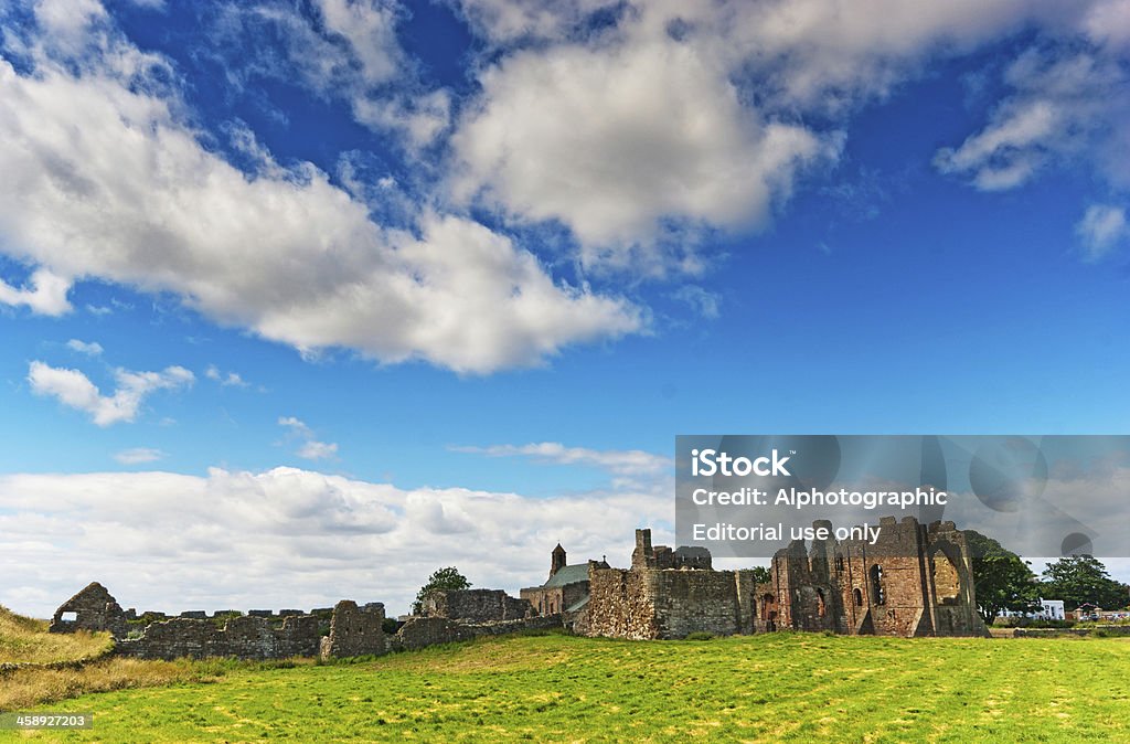 Lindisfarne Priory "Lindisfarne, England - July 27, 2012: Lindisfarne Priory ruins with polarised blue sky and fluffy white cumulus clouds." Blue Stock Photo
