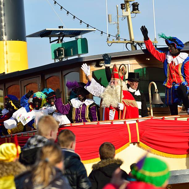 Sinterklaas Arriving Kampen, The Netherlands - November 17, 2012: Ship decorated as Stoomboot (Steamboat) is arriving at the town of Kampen for the Dutch children's Sinterklaas holiday. Sinterklaas is standing on deck and the Zwarte Pieten are dancing on the ship. Children are waving at Sinterklaas. zwarte piet stock pictures, royalty-free photos & images