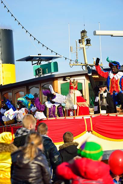 Sinterklaas Arriving Kampen, The Netherlands - November 17, 2012: Ship decorated as Stoomboot (Steamboat) is arriving at the town of Kampen for the Dutch children's Sinterklaas holiday. Sinterklaas is standing on deck and the Zwarte Pieten are dancing on the ship. Children are waving at Sinterklaas. zwarte piet stock pictures, royalty-free photos & images