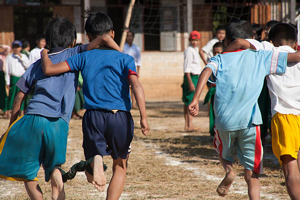 Myanmar: SChoolchildren Running Three-Legged RAce "Inle Lake, Myanmar - December 22, 2006: At Inle Lake in central Burma, two pairs of tethered schoolchildren compete in a three-legged race." three legged race stock pictures, royalty-free photos & images