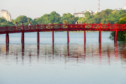 Hanoi, Vietnam - July 23, 2007: Early in the morning, Vietnamese men and women stretch, exercise, and otherwise enjoy the view on the famous Huc Bridge on Hoan Kiem Lake in the centre of Hanoi.