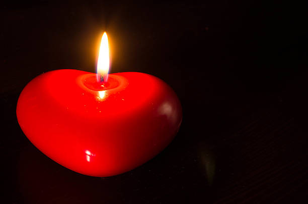 Candle in the form of heart burning in the dark