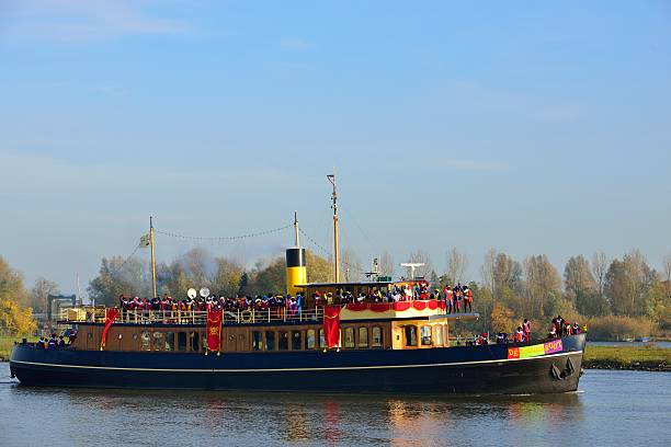Stoomboot Kampen, The Netherlands - November 17, 2012: Ship decorated as Stoomboot (Steamboat) for the Dutch children's Sinterklaas holiday. The boat is sailing on the river IJssel near the town of Kampen. Sinterklaas is standing on deck and the Zwarte Pieten are dancing on the ship. zwarte piet stock pictures, royalty-free photos & images