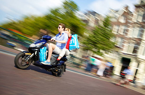 pareja joven montando en motoneta en amsterdam - keizersgracht fotografías e imágenes de stock