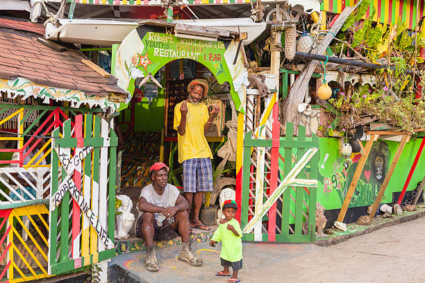 Mayreau Island, Saint Vincent and the Grenadines - December 4, 2011: smiling rasta man in front of its colorful restaurant in Old Wall, with a tired manual worker and a cute little boy. Old Wall is the only village of Mayreau Island, one of the smaller Grenadines.