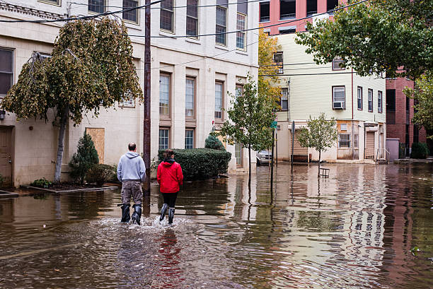 Hurrican Sandy: people walking on a flooded street "Hoboken, New Jersey, USA - October 31, 2012: Man and women walking on a flooded street" hurrican stock pictures, royalty-free photos & images