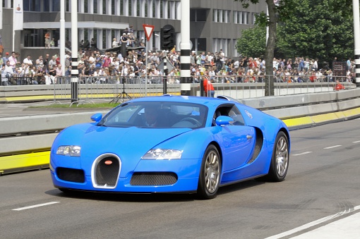 Eindhoven, The Netherlands - June 8, 2008: Blue Bugatti Veyron driving at high speed. The car is doing a demonstration driving during the 2008 Pole Position event. People in the background are looking at the car.