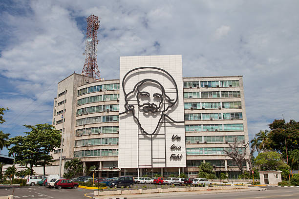 Habana, Cuba - September 6th, 2011: Camilo Cienfuegos sculpture in front of Communications Ministry building in the Revolution Square. Most of the cars parked in front are old models made in Russia. 