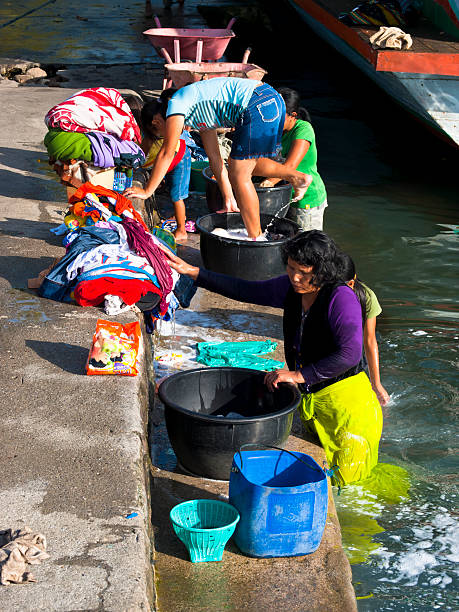 washing "Samosir, Indonesia - June 9, 2009: Group of women from island Samosir is washing their family clothes in the waters of lake Toba on boat pier. In front of them are bowls with water and in some of them are washed clothes" danau toba lake stock pictures, royalty-free photos & images