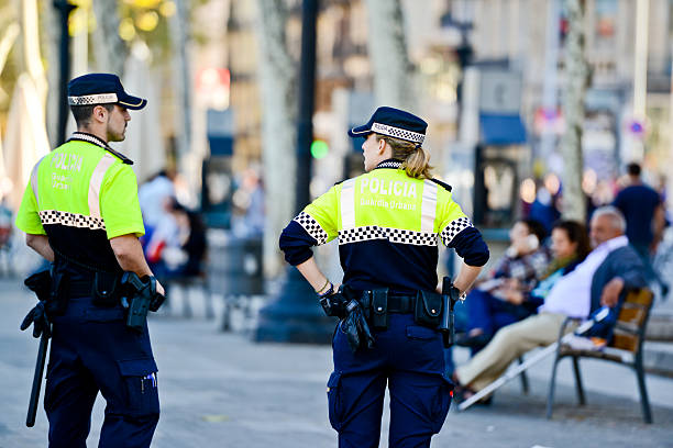 Policeman and Policewoman in Barcelona, Spain "Barcelona, Spain- October 15, 2012: Policeman and Policewoman standing on the street in Barcelona, Spain, observing people and doing their job. People relaxing on bench" police policewoman women spain stock pictures, royalty-free photos & images