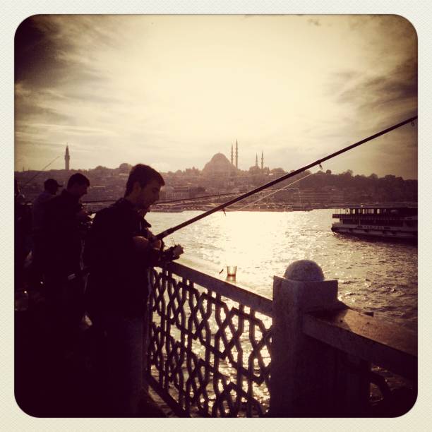 uomo di pesca sul ponte di galata a istanbul - mobilestock istanbul turkey day foto e immagini stock