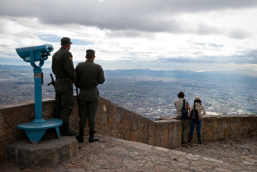Bogota, Colombia - May 28, 2009: Two visitors to Monserrate, a mountain rising above the city center of Bogota, enjoy the tremendous view of the city. Two policemen are also watching.