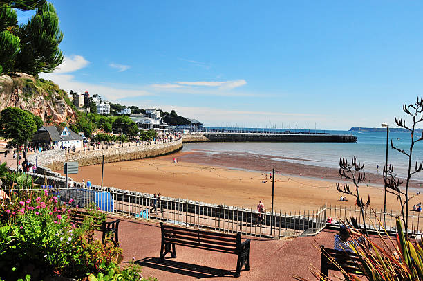 Torquay Beach "Torquay, UK - August 27, 2010: People relaxing in the sunshine. Torquay Beach with the marina and town beyond. The marina wall can be seen mid picture and is a major small boat harbour in Devon." Devon stock pictures, royalty-free photos & images