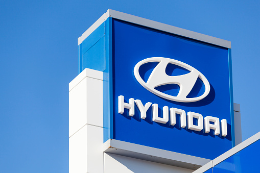 Halifax, Nova Scotia, Canada - December 11, 2011: Hyundai sign and logo above car dealership lot over building and showroom with clear, blue sky in background. Hyundai Motor Company was founded in 1967 and is known for producing the Hyundai Sonata, the Tuscani/Tiburon, the Sante Fe, the Tuscon, and the flagship Genesis Coupe and Sedan.