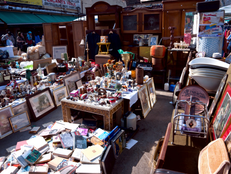 Milan, Italy - July 2, 2022: A collection of random and assorted used items at a flea market vendor's table in the Canal District in Milan