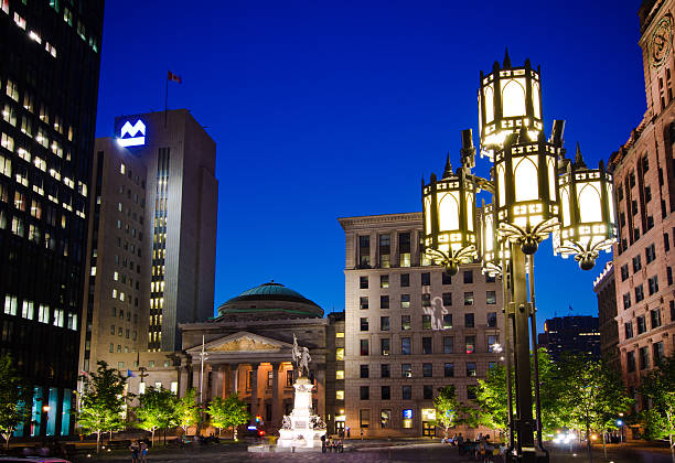 Place d'Armes in Montreal, Quebec at night "Montreal, Canada - August 25, 2012: People mill about Place d'Armes in the Old Montreal section of Montreal at night. Place d'Armes is the second oldest public site in Montreal, it was called Place de la Fabrique when it was first developed in 1693, at the request of the Sulpicians, then later renamed Place d'Armes in 1721 when it became the stage of various military events." place darmes montreal stock pictures, royalty-free photos & images