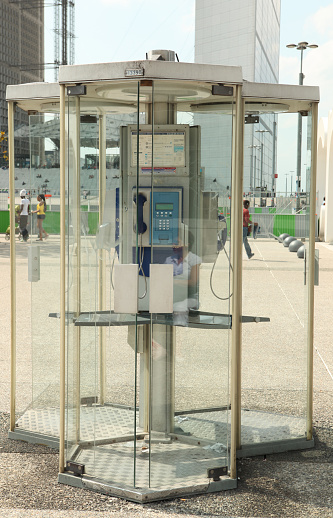 Puteaux, France - August 3, 2011: France Telecom Public telephone booths in front of La Grande Arche in the business district of La Defense, west of Paris, France. You can see also people in the background. France Telecom S.A. is a French telecommunications company in France, the third-largest in Europe and one of the largest in the world. 