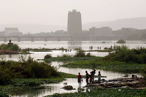 Bamako "Bamako, Mali - March, 18th 2006 - People in silhouette bathe and do laundry in the Niger River with the skyline of Bamako and the BCEAO tower in the distance" Mali stock pictures, royalty-free photos & images