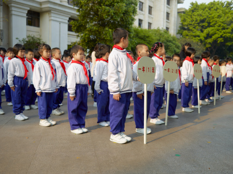 Guangzhou, China - March 26, 2012: Chinese school children in a row and their teacher, getting ready to go to their classes in the morning, on the Shamian island of Guangzhou.