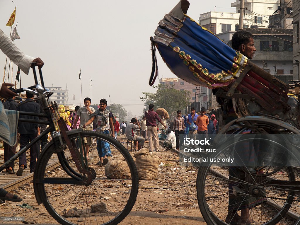 Overpopulation problem in Dhaka capital city of Bangladesh "Dhaka, Bangladesh - January 23, 2012: Rickshaw drivers passing over the railroad tracks where people calmly walking." Asia Stock Photo