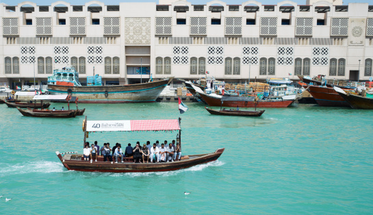 Dubai, UAE - March 11, 2012: Dubai public transportaion on water with passengers. These small wooden boats, called abra, go across the Dubai creek all day long and to transport people. A surprisingly cheap transportaion for Dubai, a trip accross the creek costs about 0.25 Euro.