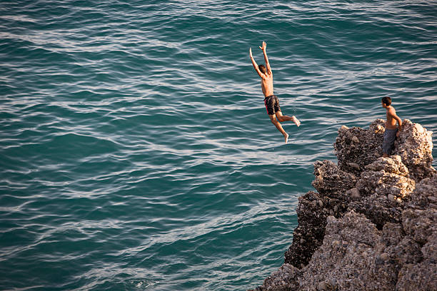Boys Diving from Nerja Cliffs "Nerja, Spain - August 24, 2009: Boy diving from Nerja Cliffs into the Mediterranean sea waters, in Nerja, Andalucia, Spain" cliff jumping stock pictures, royalty-free photos & images