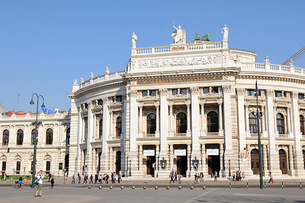 The Burgtheater Imperial Court Theater in Vienna (Austria) "Vienna, Austria - April 19, 2011: Busy people passing by the place in front of The Burgtheater (Imperial Court Theatre) in Vienna (Austria) in an april spring time day. In front a man taking pictures. On the building exterior of Burgtheater are to be read names of well known poet as Lessing, Goethe, Schiller. The Theatre opened first time back in 1776. Centre of Vienna." burgtheater vienna stock pictures, royalty-free photos & images