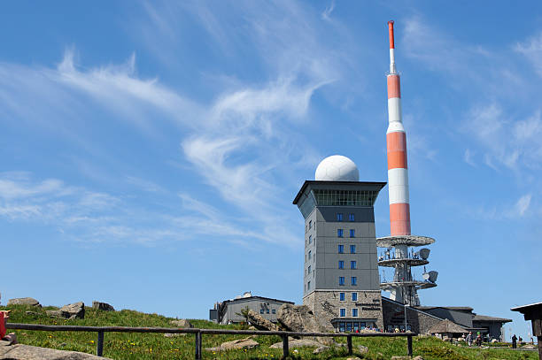 Peak of Brocken Mountain at Harz National Park (Germany) "Brocken, Germany - May 26, 2012: Peak of Brocken Mountain at Harz National Park (Saxony-anhalt, Germany) with its typical red white communication tower and the Hotel at Brocken with two restaurants. People walking around in the path leading across the peak of Brocken Mountain." sendemast stock pictures, royalty-free photos & images