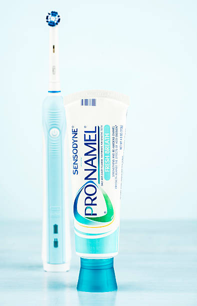 Dental Care "Suffolk, Virginia, USA - August 27, 2012: A vertical studio shot of a tube of Sensodyne Pronamel toothpaste with a brand new Oral-B electric toothbrush defocused in the background. This model of toothbrush is the Professional Care 1000." sensodyne stock pictures, royalty-free photos & images