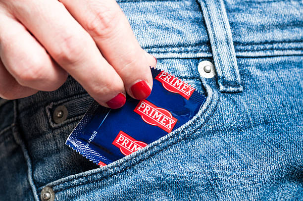 prenant préservatif de la poche de jeans - sex condom jeans horizontal photos et images de collection