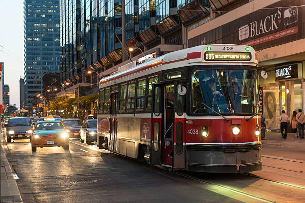 Streetcar on Dundas "Toronto, Canada - May 18, 2012: A Toronto Transit Commission streetcar pauses on Dundas Street West in evening light to pick up passengers." sustainable energy toronto stock pictures, royalty-free photos & images