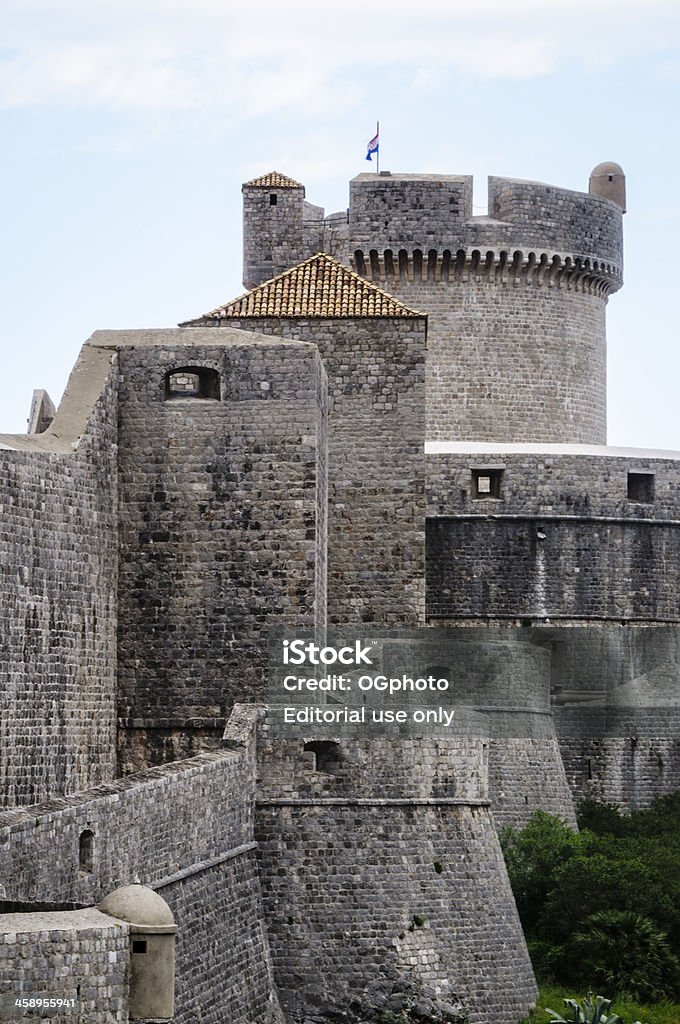 Exterior walls of the city Dubrovnik with Minceta tower, Croatia "Dubrovnik, A!roatia - May 7, 2012: Image of the exterior walls of the city of Dubrovnik with the Minceta tower at the back with the Croatian flag.  Image taken from outside the fortified city of Dubrovnik." Ancient Stock Photo