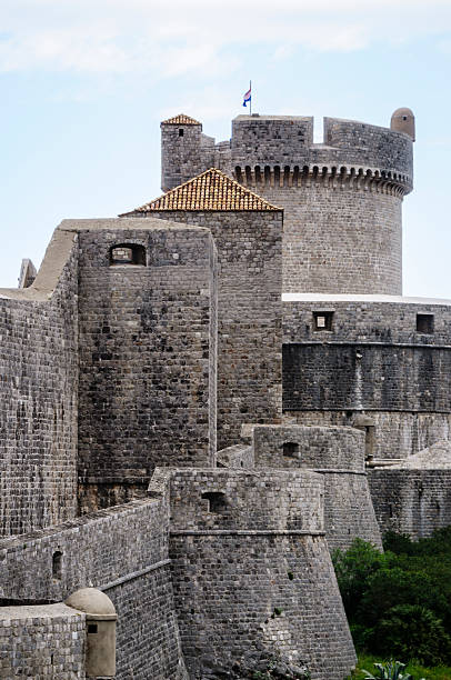 Exterior walls of the city Dubrovnik with Minceta tower, Croatia "Dubrovnik, A!roatia - May 7, 2012: Image of the exterior walls of the city of Dubrovnik with the Minceta tower at the back with the Croatian flag. Image taken from outside the fortified city of Dubrovnik." fort minceta dubrovnik stock pictures, royalty-free photos & images