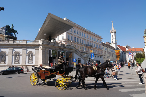 Vienna, Austria - April 9, 2012: Horse carriage passing by Albertina museum in Vienna. Museum is located in Albertina platz in the center of the city. Manay horse carriage on this square wait for tourist.