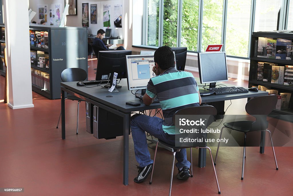 Jeune homme travaillant sur ordinateur dans la bibliothèque moderne, Danemark - Photo de Bibliothèque libre de droits