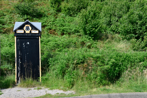 Cappercleuch, Scotland, UK - August 10, 2012: A weathered AA box at the side of the road. An AA (Automobile Association) box used to be a common sight on the side of British roads. The boxes contained a telephone to allow members of the AA to phone if they required assistance. As mobile phones became more common these boxes became less important and were phased out in 2002.